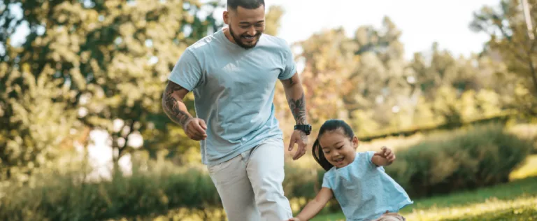 Father and toddler playing soccer in field
