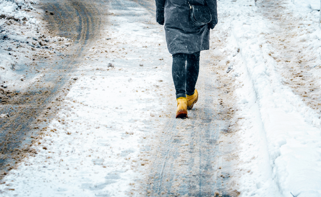 Ice on sidewalk as woman is walking