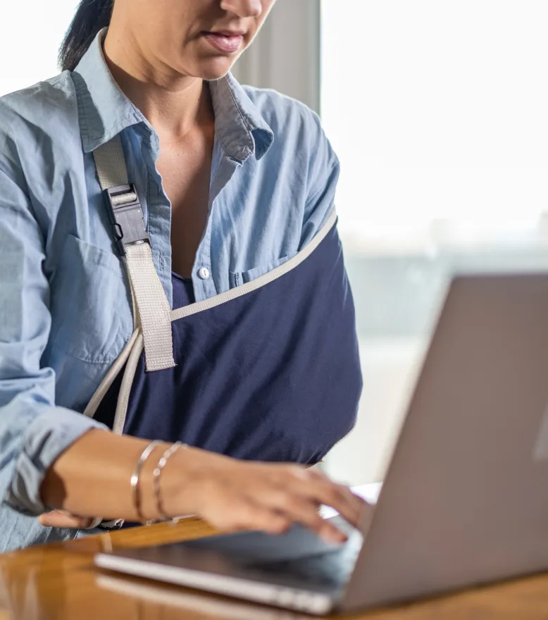 Injured woman filling our a personal injury claim on the computer.