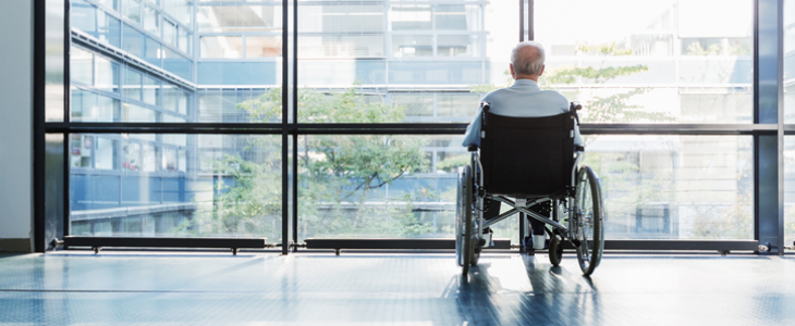Man sitting in a wheelchair while staring out the window at a neglectful nursing home