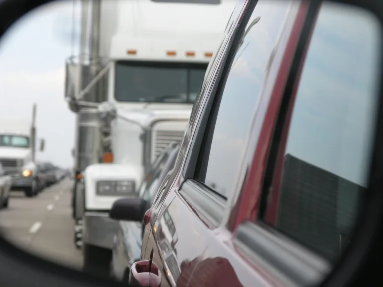 View of semi-truck and traffic in car's side mirror on a busy highway