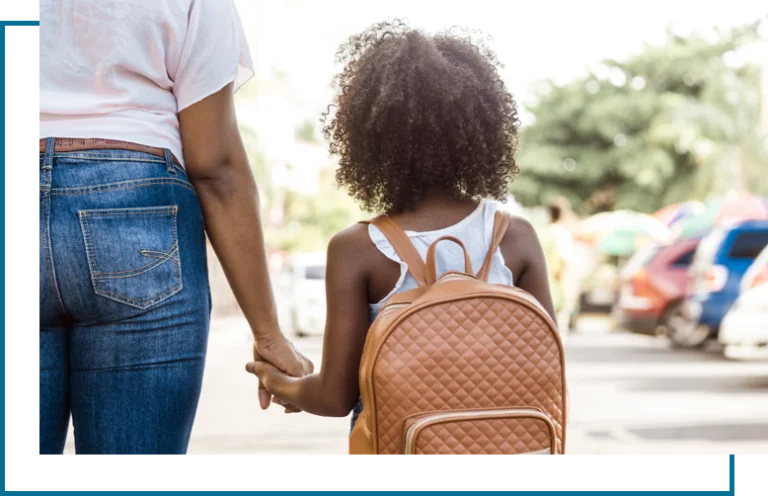 Mother holding daughter's hand as she waits to be picked up by her father.