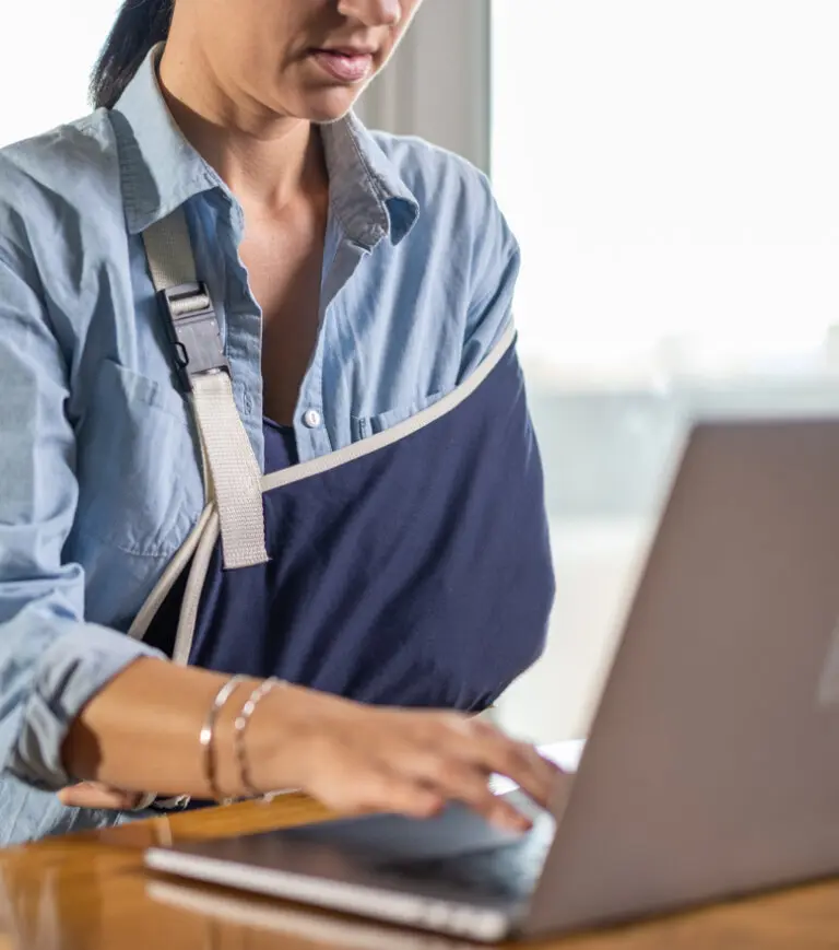 Injured woman filling our a personal injury claim on the computer.