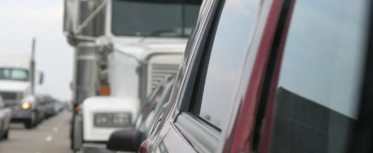 View of semi-truck and traffic in car's side mirror on a busy highway